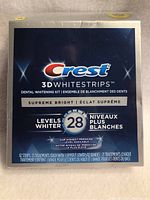 Front view of Crest 3D Whitestrips Supreme Bright box showing branding and product details including 'Levels Whiter 28' and quantity of 42 strips (21 treatments).