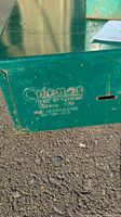Close-up of Coleman logo and model number 425 on green metal stove.