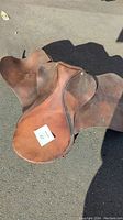 Top view of used brown leather English riding saddle showing full seat and flaps.