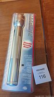Front view of unopened silver Maglite flashlight in original packaging showing the product and branding details.