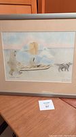 Framed print showing an Inuit man walking beside a sled dog pulling a load in a snowy environment.