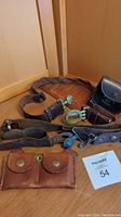 Overview of two leather belts, two leather pouches, and associated scouting gear items on wooden surface.