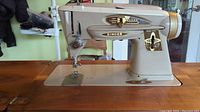 Side view of vintage beige Singer sewing machine with stitch pattern and tension controls.
