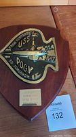 Front view of wooden shield plaque showing gold and black submarine emblem and USS Pogy SSN 647