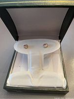 Pair of 14K gold heart-shaped stud earrings with pink stones displayed in a jewelry box.