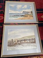 Photo of both framed watercolour paintings showing seaside scenes, the beach and harbor.