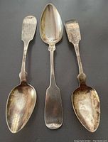 Photo showing three different silver spoons with visible tarnish and varied bowl shapes.