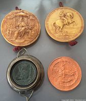 Four seals arranged flat on a grey background showing detailed reliefs and cord attachments.