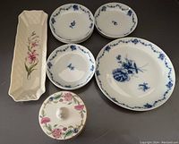 Photo of all items together showing Belleek tray, Minton covered jar, and Fürstenberg plates, arranged on black surface.