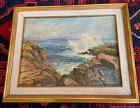 Full view of the framed oil painting showing rocky coastline with ocean waves.