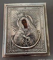 Front view of the rectangular silver icon showing Virgin Mary with detailed silver crown, halo, and floral motifs around painted face on wood.