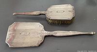 Top view of the vintage sterling silver brush and mirror set, showing the handle and the engraved floral details with initials EL.