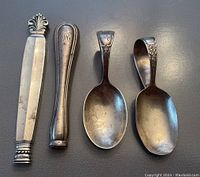 Top view of 2 utensil handles and 2 baby spoons showing design and markings on top side.