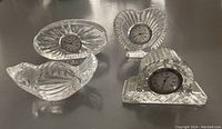 Three Waterford crystal quartz clocks and one bird paperweight arranged on a surface, showing overall shapes and design.