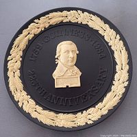 Black Jasperware plate with beige relief border of barley and hops and central relief bust with commemorative text for Guinness 225th anniversary.