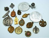 Top view of 17 religious icons, medals, prayer tokens in silver and gold tone, showing images of saints and religious symbols.