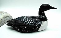 Side angle showing the detailed black and white hand painted pattern mimicking loon feathers and the red eye detail on a ceramic bird figurine.