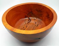Angled side view of the large hand turned wooden bowl showing the depth, wood grain, and natural markings.