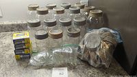 Photo showing multiple glass jars of various sizes with metal lids, extra lids and bands in plastic bag, boxes of rubber fruit jar rings.