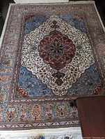 Full view of rug flat on floor showing central medallion and border details.