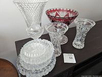 All crystal vases and ashtrays on dark wooden surface, showing full lot.