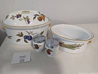 Set of four pieces including large and medium casserole dishes and two egg coddlers shown from the front with fruit and vegetable designs.