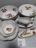 Photo showing 10-inch salad bowl, gravy boat with saucer, fruit bowls and pickle dish with botanical fruit and vegetable artwork and gold trim edges.