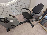 Side view of the FreeSpirit recumbent exercise bike showing the padded seat and backrest and folding frame