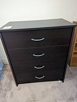 Front view of a 4-drawer tall dresser with dark wood veneer and silver curved handles, showing overall condition and style.