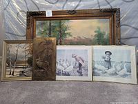 Full overview of all wall art laid on floor showing five items: large landscape oil painting, smaller birch tree oil painting, two framed prints of children with geese, and a decorative metal relief.