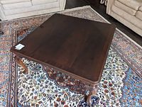 Top view of dark brown solid wood square coffee table placed on patterned rug.