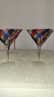 Close-up view of three Pier 1 martini glasses showing multicolour diagonal stripes on the bowl.