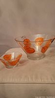 Two clear glass bowls with orange leaf patterns and gold accents, one large (chip bowl) and one smaller (dip bowl)