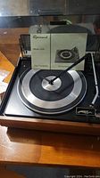 Full view of Garrard Model 3500 turntable with instruction manual positioned upright against the dust cover.