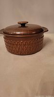 Front side view of the brown Wedgwood Pennine casserole with lid showing embossed arch pattern.