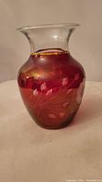 Front view of vintage red etched glass vase with floral cornflower design etched onto the body, clear neck, and gold rim trim.