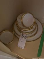 Stack of Aynsley Elizabeth china including plates and cups with gold trim, some viewed from the bottom.