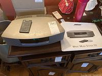 Bose Wave Music System III unit with remote on top and manual beside it