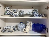 Wide view of upper and lower cabinet shelves displaying all porcelain and glass pieces.