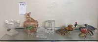 Full view of all nine items displayed on a shelf: stone bird bath with birds, pink glass dish, cut glass trinket box, ceramic and enamel bird figurines.