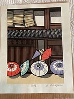 Full view of Japanese block print showing five colorful umbrellas and wooden building facade.