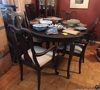 Round mahogany wood dining table with four matching chairs and various items on tabletop, showing general overall view and condition
