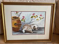Overall view of the framed watercolor painting showing a sleeping cat next to a brown pot with flowering branches, with mat and gold frame.