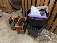 Photo showing arrangement of three terracotta planters, metal planter bucket, and black plastic pots with additional accessories on top.
