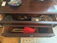 Two open drawers showing multiple purses and makeup bags of various colors, styles, and materials including Michael Kors wristlet and fabric embroidered bags.