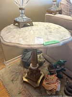 Side view showing marble scalloped top and detailed metal pedestal base.