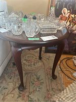 Side view of round wooden side table showing cabriole legs and curvature details