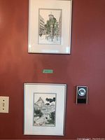 Two framed prints of Vancouver scenes on a red wall, showing general size and framing, with one above the other near a thermostat.