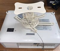 Top view of the white Panasonic LCD projector with mounted adjustable bracket showing mounting holes and cable.