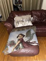 Photo of leather chaise with 'good night' pillow and an angel throw blanket showing the leather texture and wear.